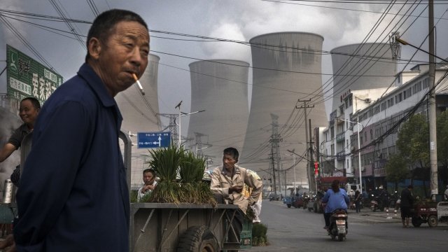 Street vendors stand in front of a coal-fired power plant