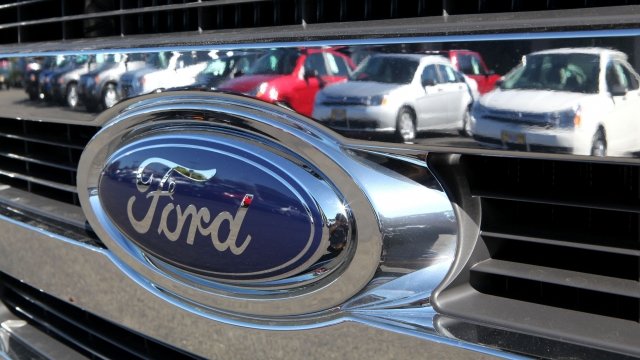 Cars are reflected in the grill of a new Ford truck.