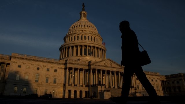 A person walks by as the sun rises near The United States Capitol Building.