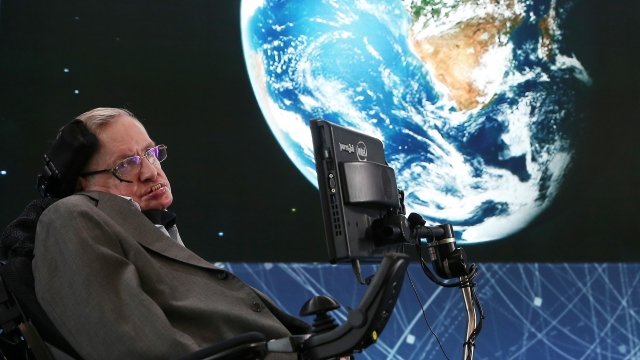 Stephen Hawking in front of a projection of Earth