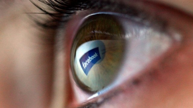 The Facebook logo is reflected in an eye.