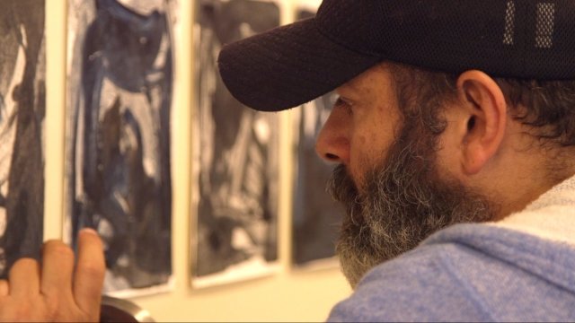 Artist Richard Santiago in front of his art exhibition