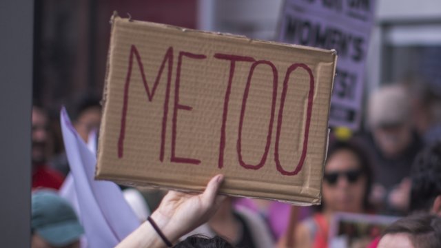 Woman holds 'Me Too' sign.