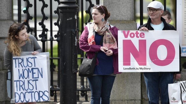 Residents in Ireland hold protest signs about the country's abortion referendum