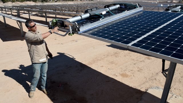 SunPower field supervisor Oscar Madrigal demonstrates using a panel washing robot on a row of solar panels.