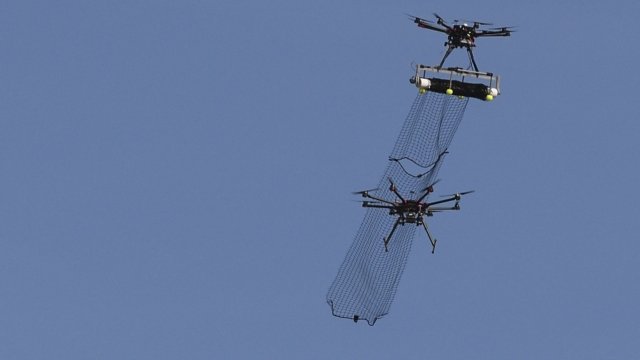 A drone helicopter captures another drone helicopter in a net