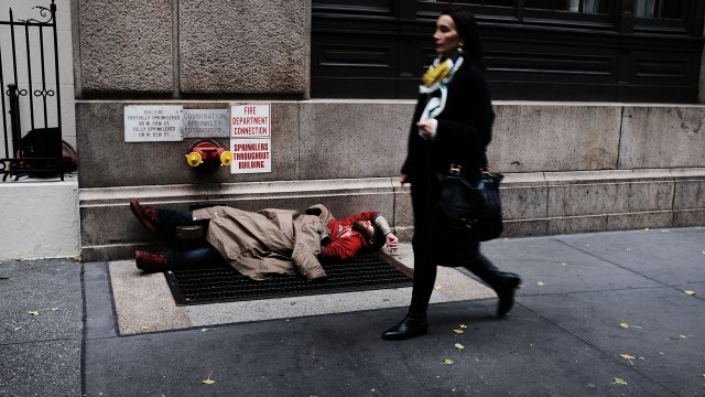 A woman walks by a homeless man along a Manhattan street on November 30, 2017 in New York City.