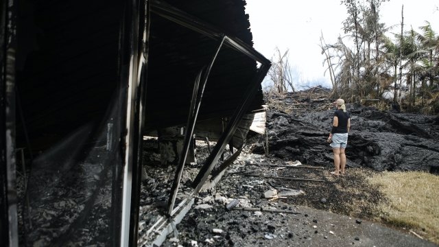 A woman stands outside a house that was damaged by lava from Hawaii's Kilauea volcano