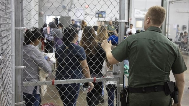 A customs officer and migrants at a processing facility.