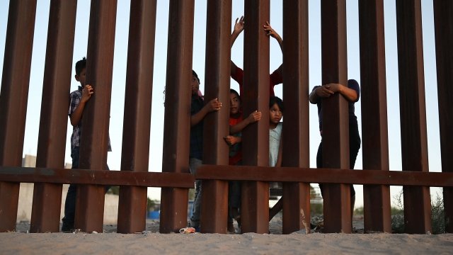Children look through a border fence