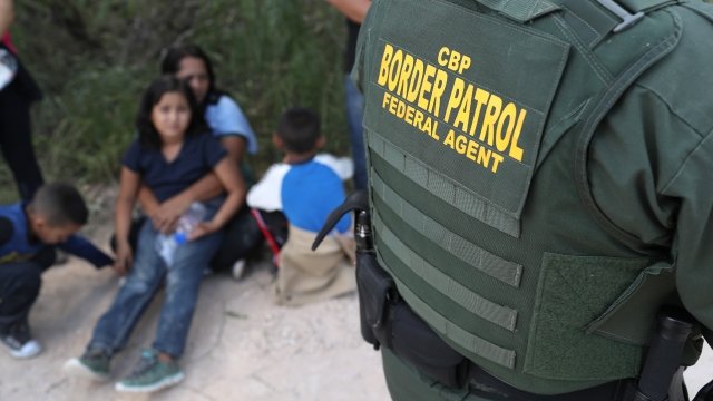 Central American asylum seekers wait as U.S. Border Patrol agents take them into custody.