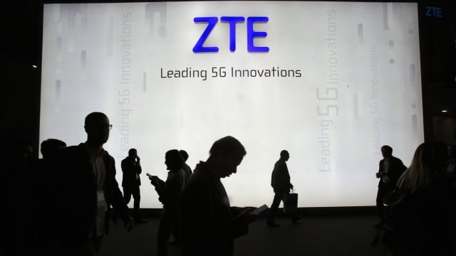 People walking past a ZTE banner