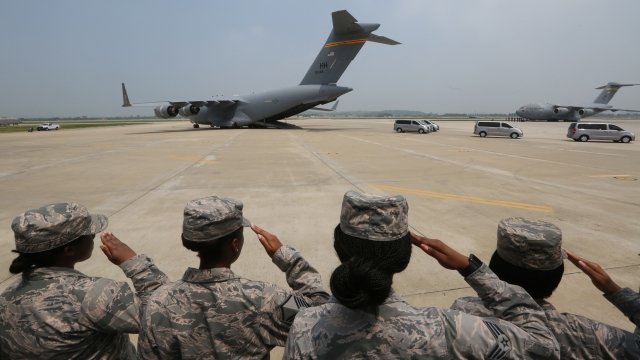 U.S. Army soldiers salute as vehicles carrying probable remains arrive at a military base in South Korea