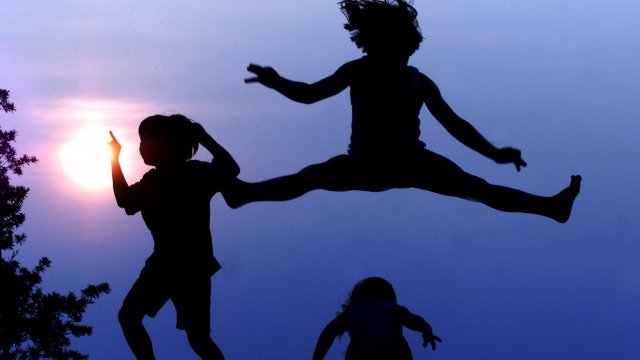 Three children jump on a trampoline