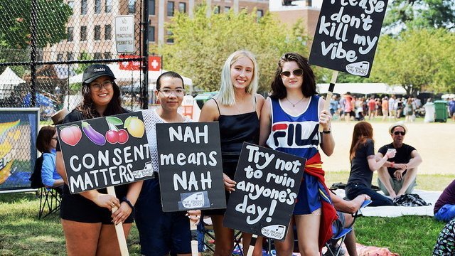 Festival-goers hold Our Music My Body signs against sexual harassment