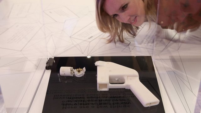 A woman looks at a 3D-printed handgun