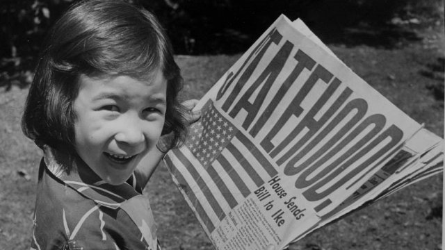 Girl holds newspaper with "Statehood" headline