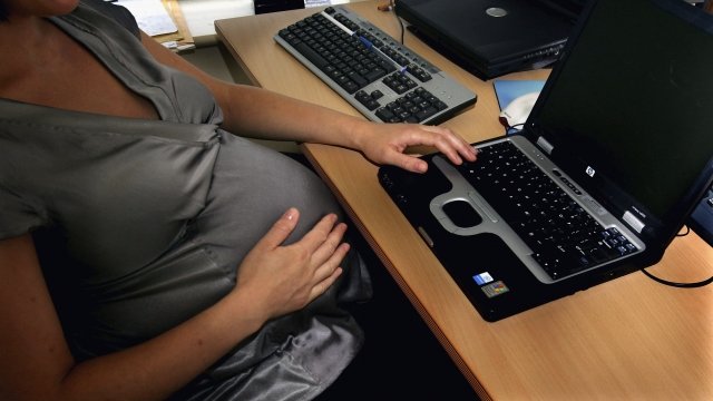 Pregnant mother sits at desk