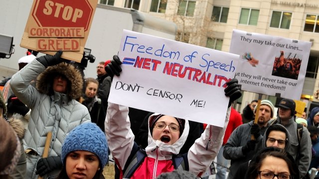 Protesters hold signs supporting net neutrality