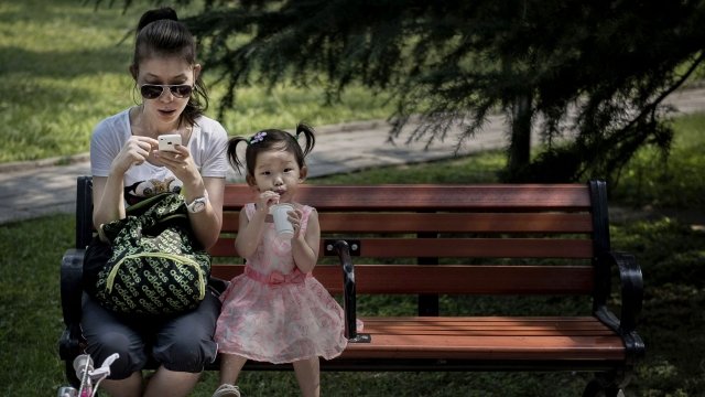 A woman sits next to her daughter on a bench in China