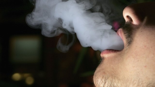 A person blows smoke from an e-cigarette