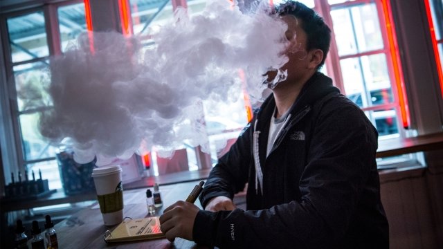 Man vapes, or smokes an electronic cigarette