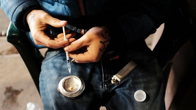 A man holding a syringe to use for heroin.
