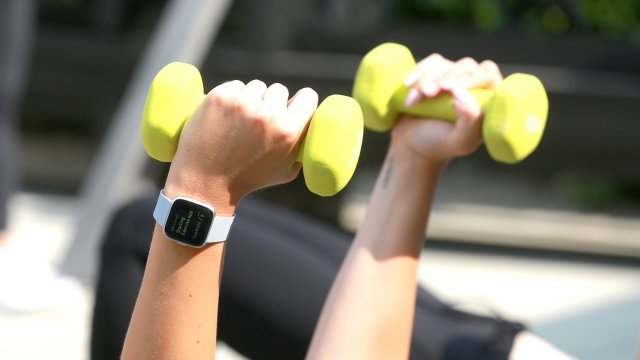 A person lifts weights with a smart watch on