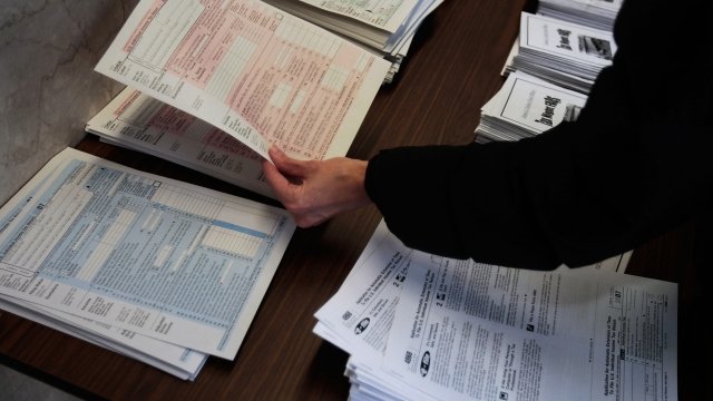 A person picks up tax forms from a table