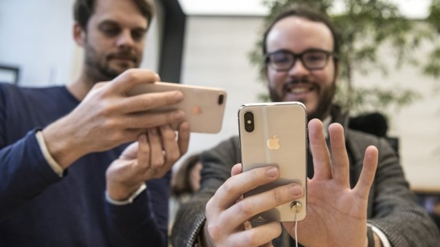 Two men use iPhones inside an Apple store