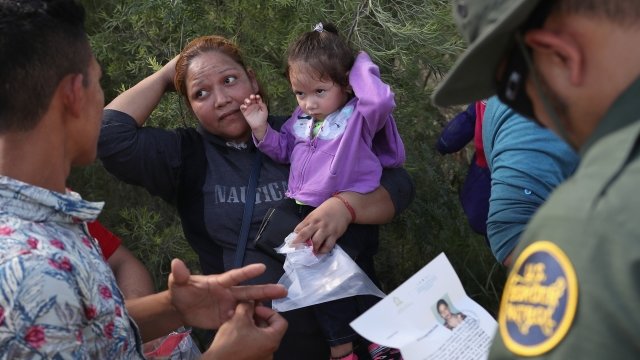 A U.S. Border Patrol agent talks to a migrant mother and daughter before taking them into custody on June 12, 2018.
