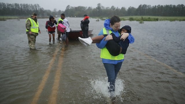 A volunteer carries a young girl out of flood waters in North Carolina