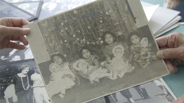 An old photograph depicts Estrella Alamar with her sisters sitting by a Christmas tree.