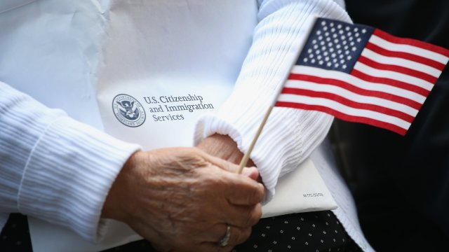 Woman holds a citizenship packet and American flag