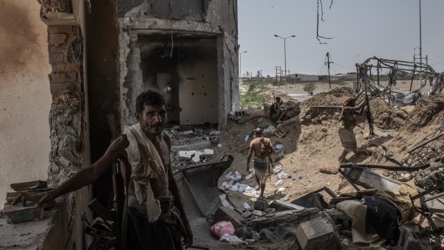 A Yemeni man standing in front of a destroyed building