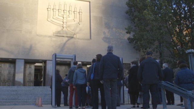 Mourners wait outside a synagogue