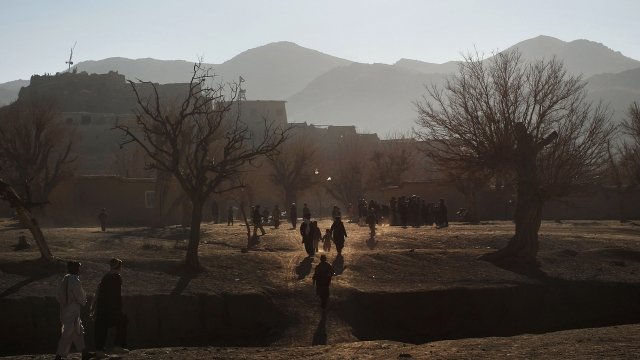 Afghan residents walk toward village