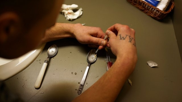 Person loads needle with heroin.