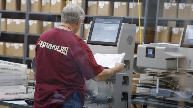 An elections worker feeds ballots into a tabulation machine