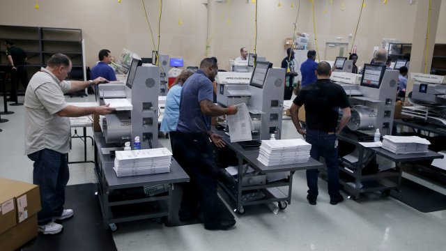 Election officials load ballots into machines