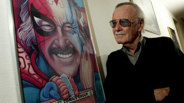 Stan Lee beside a Spider-Man poster