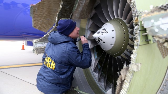 NTSB investigator Jean-pierre Scarfo examines damage to the CFM International 56-7B turbofan engine.