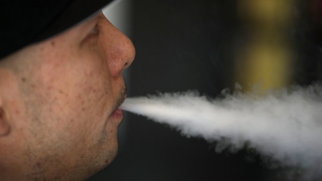 A man exhales vapor from an e-cigarette