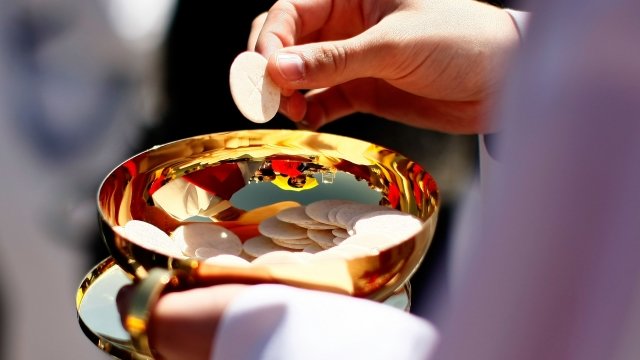 Priest holds Holy Communion wafer