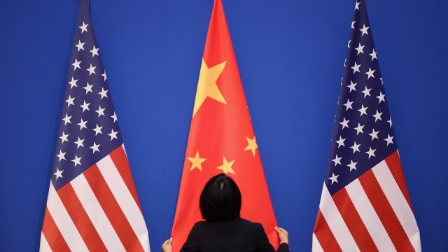 Woman arranging Chinese flag in between two U.S. flags.