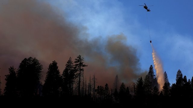 A helicopter drops water on top of a fire near Cresta, California