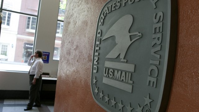 A man walks by a sign in the lobby of a post office.