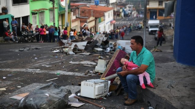 Venezuelan father holds his daughter on a street corner