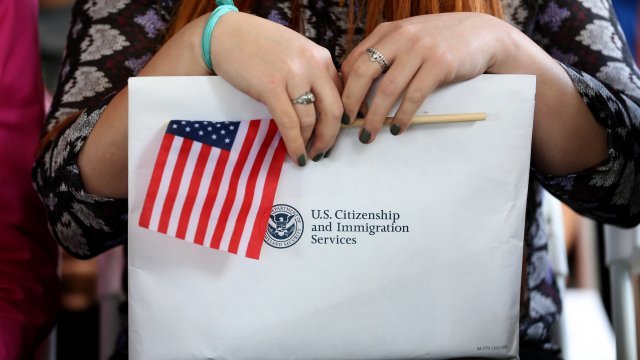 A woman holds an American flag and a U.S. Citizenship and Immigration Services envelope