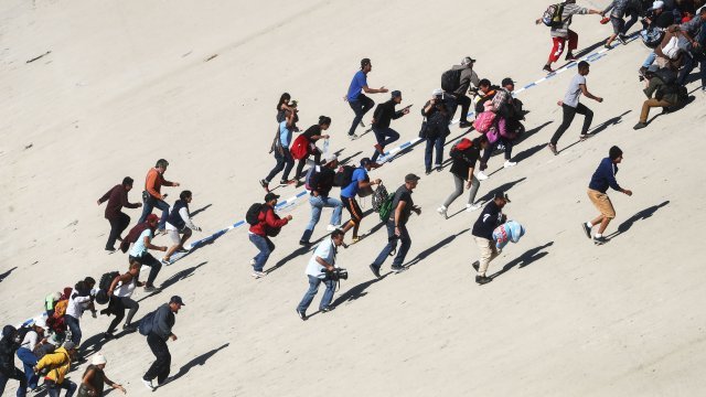 Migrants attempt to make their way past a police blockade in Tijuana, Mexico